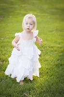 adorable petite fille vêtue d'une robe blanche dans un champ d'herbe photo