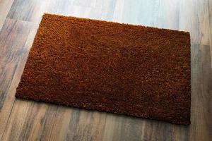 Tapis de bienvenue brun foncé vierge sur fond de plancher en bois prêt pour votre propre texte photo