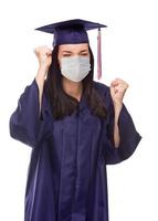 femme diplômée portant un masque médical et une casquette et une robe acclamant isolé sur fond blanc photo