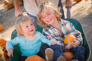 adorable petit garçon joue avec sa petite sœur dans un ranch rustique au champ de citrouilles. photo