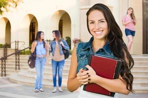 Étudiante de jeune fille de race mixte avec des livres scolaires sur le campus photo