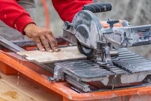 Travailleur utilisant une scie à carreaux humide pour couper des carreaux muraux sur un chantier de construction photo