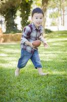 mignon jeune garçon métis jouant au football à l'extérieur photo