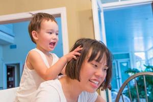 heureux métis chinois et caucasien garçon s'amusant avec une mère chinoise à l'intérieur de la maison photo