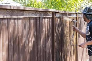 peintre professionnel pulvérisant une clôture de jardin avec tache photo