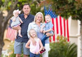 heureuse jeune famille caucasienne devant des maisons avec des drapeaux américains photo