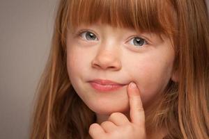 portrait amusant d'une adorable fille aux cheveux rouges sur gris photo