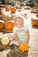 adorable petite fille tenant une citrouille au champ de citrouilles photo