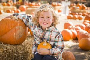 petit garçon assis et tenant sa citrouille au champ de citrouilles photo