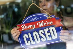 femme triste propriétaire d'un magasin tournant le signe pour fermer la fenêtre photo