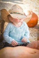 adorable petite fille avec un chapeau de cow-boy au champ de citrouilles photo