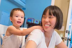 heureux métis chinois et caucasien garçon s'amusant avec une mère chinoise à l'intérieur de la maison photo