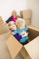 jeune famille dans une pièce vide jouant avec des cartons de déménagement photo