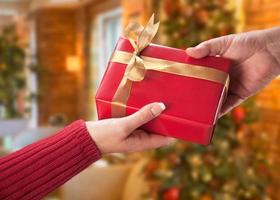 échange de cadeaux homme et femme devant le sapin de noël décoré. photo