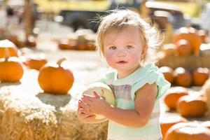 adorable petite fille tenant une citrouille au champ de citrouilles photo
