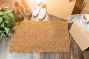 tapis de bienvenue home sweet home, cartons de déménagement, chaussures femme et homme et plante sur parquet photo