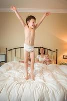 garçon chinois et caucasien de race mixte sautant au lit avec sa famille photo