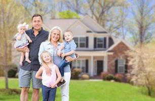 heureuse jeune famille caucasienne à l'extérieur devant leur nouvelle maison photo