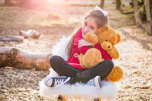 jolie jeune fille métisse étreignant un ours en peluche à l'extérieur photo