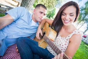 jeune fille adulte jouant de la guitare avec son petit ami dans le parc. photo