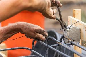 Travailleur sécurisant l'ossature d'armature en acier avec une pince à fil sur le chantier de construction photo