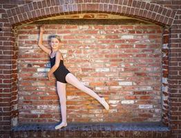 jolie fille de ballerine caucasienne postant contre un mur de briques photo