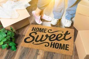 homme et femme debout près du tapis de bienvenue home sweet home, boîtes de déménagement et plante photo