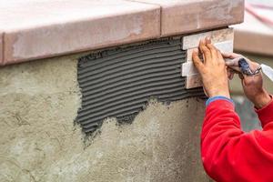 travailleur installant des carreaux de mur sur un chantier de construction photo