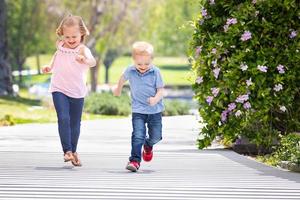 jeune soeur et frère s'amusant à courir au parc photo