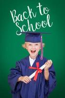 jeune garçon caucasien en chapeau de graduation et robe sur fond de tableau vert avec retour à l'école photo