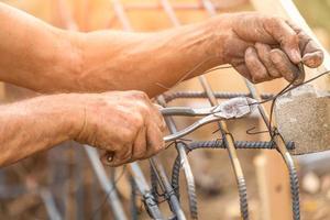 Travailleur sécurisant l'ossature d'armature en acier avec une pince à fil sur le chantier de construction photo