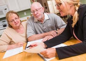 couple d'adultes âgés passant en revue des documents dans leur maison avec un agent lors de la signature photo