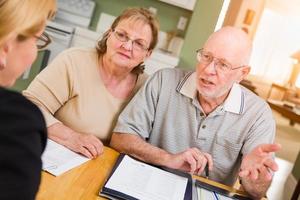 couple d'adultes âgés passant en revue des documents dans leur maison avec un agent lors de la signature photo