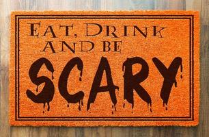 manger, boire et être effrayant tapis de bienvenue orange halloween sur fond de plancher en bois photo