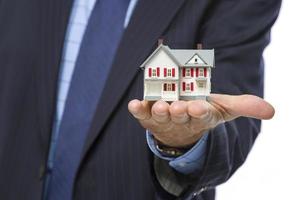 agent immobilier masculin tenant une maison miniature dans la paume photo