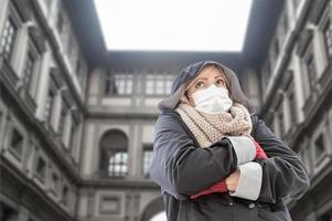 une jeune femme portant un masque facial se promène près de la galerie des offices en italie photo