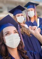 plusieurs diplômées en bonnet et robe portant des masques médicaux photo