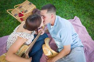 jeune couple adulte avec guitare s'embrasser dans le parc. photo