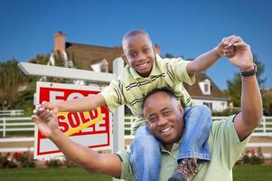 père et fils devant l'enseigne immobilière et la maison photo