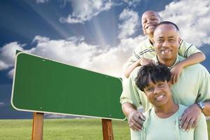 famille afro-américaine devant un panneau de signalisation vert vierge photo