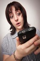femme brune stupéfaite utilisant un téléphone portable photo