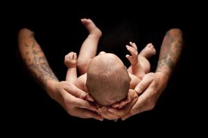 mains du père et de la mère tenir bébé nouveau-né sur fond noir photo