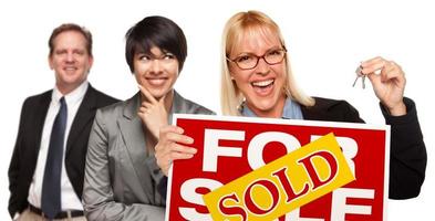 équipe immobilière avec femme tenant les clés et signe vendu à vendre photo