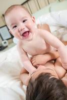 Métis chinois et caucasiens bébés frères s'amusant allongés sur leur couverture photo