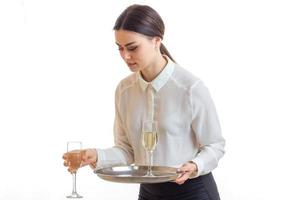 jeune serveuse sérieuse en uniforme avec des verres de vin dans les mains photo