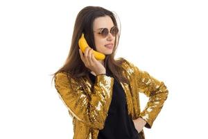 femme brune joyeuse en veste dorée tenant une banane photo