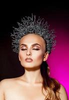 portrait vertical d'une femme à la mode avec le maquillage des yeux fermés et une couronne sur la tête photo