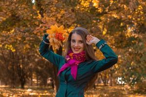 fille gaie en foulard rose a levé les mains sur la tête garde les feuilles et les sourires photo