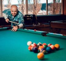 l'homme commence à jouer au billard et casse la pyramide de boules sur la table photo