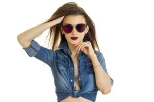 dame chaude en veste de jeans sans soutien-gorge regarde la caméra en lunettes de soleil photo